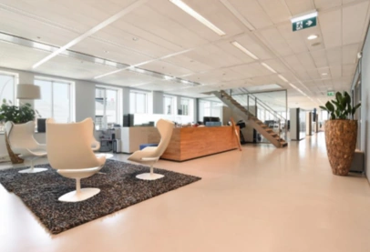 Modern kantoorinterieur aan de Barbara Strozzilaan met witte stoelen, houten balie en open werkruimte.